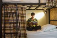 un hombre sentado en una cama leyendo un libro en Hostal Don Cenobio, en Flores