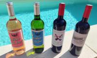 drie flessen wijn staan op een tafel naast een zwembad bij Love Room "Les Secrets de Winna" in Augé
