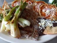Un plato de comida con carne y verduras encima. en Hotel y Balneario San Fernando, en Ojuelos