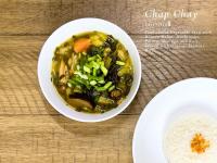 Phumĭ Bântéay SreiにあるThe Little Vegan Homestayのテーブルの上に野菜とご飯が入ったスープのボウル