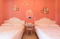 two beds in a room with orange walls and a mirror at Wei Sen House in Hualien City