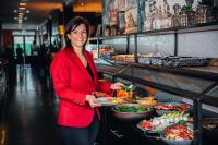 a woman standing in a buffet line with a plate of food at Van der Valk Hotel Leiden in Leiden