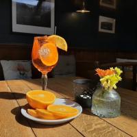 Un vaso de jugo de naranja sobre una mesa con rodajas de naranja. en The Rhu Inn, en Rhu