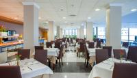 un comedor con mesas blancas y sillas marrones en Hotel RH Gijón & Spa, en Gandía