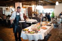 a man holding a plate of food on a table at KABAN BOUTIQUE HOTEL - 5Star Central Villa in Vatra Dornei in Vatra Dornei