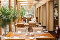 um restaurante com mesas e cadeiras de madeira e janelas em Palavra Resort em Manama