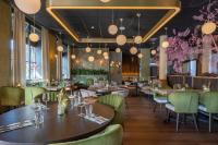 ein Restaurant mit Holztischen und grünen Stühlen in der Unterkunft Leonardo Hotel Breda City Center in Breda