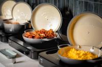 a kitchen with three pans with food in them at Radisson Hotel Leipzig in Leipzig