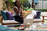 een vrouw op een bank voor een laptop bij Sweetfield Manor in Bridgetown