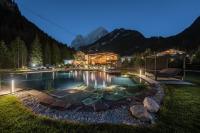 una casa con piscina por la noche con montañas en Hotel Majon Miramonti, en Canazei