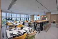Un restaurante con mesas, sillas y ventanas. en Home2 by Suite Wuhan Qingshan, en Wuhan