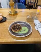 Un plato con una galleta sobre una mesa con una copa de vino. en B&B HOTEL Chaumont, en Chaumont