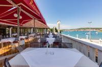 Un restaurante con mesas y sillas blancas y el océano. en Mobile homes Jezera Lovišća Premium, en Jezera