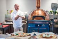 Ein Mann steht in einer Küche mit einem Pizzaofen in der Unterkunft Peakture Hotel Balvanyos in Balvanyos