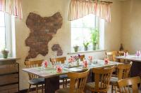 una sala da pranzo con tavoli, sedie e finestre di Gasthaus Stollmühle a Stützengrün