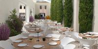 un restaurante con mesas, sillas blancas y plantas en Le Grand Hôtel Dieu by SOWELL COLLECTION, en Nimes