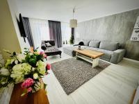 sala de estar con sofá, mesa y flores en Kwartał Dominikański, en Kamień Pomorski