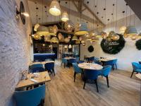 un restaurante con mesas, sillas azules y lámparas de araña en Le Petit courault, en Pamproux