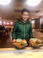 a man holding two plates of hamburgers and french fries at Namche Terrace in Namche