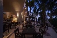 um restaurante com mesas e cadeiras de madeira e palmeiras em De' Tuva Resort Mui Ne em Mui Ne