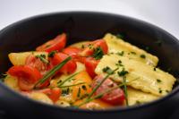 a black bowl of food with tomatoes and cheese at Hotel Virgilio in Riva del Garda