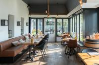 バドフーフェドルプにあるBoutique Hotel Herbergh Amsterdam Airport FREE PARKINGのテーブルと椅子と窓のあるレストラン