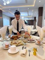 a man in a tie preparing food on a table at Hotel MEDINA in Oran