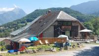 a building with chairs and umbrellas in front of it at Yourtes Olachat proche Annecy in Faverges
