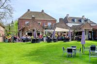 een groep mensen die aan tafels in een tuin zitten bij Appartement Nu in Eersel