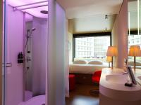 a bathroom with a sink and a bedroom with a bed at citizenM Southwark Bankside in London