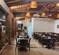 een eetkamer met tafels, stoelen en lampen bij Santa Areia Lençóis Pousada in Santo Amaro