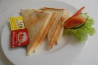 Hotel Dhyana Pura في Kapal: طبق أبيض يعلوه شطيرة وخضروات