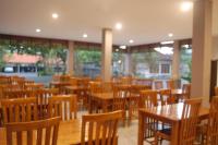 Hotel Dhyana Pura في Kapal: مطعم فارغ بطاولات وكراسي خشبية