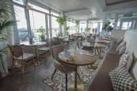 カトウェイクにあるHotel Steeds aan Zeeのテーブルと椅子と窓のあるレストラン