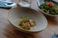 Un tazón blanco de comida sobre una mesa de madera en Bukit Samudra, en Lemonga