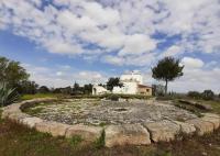 a large stone circle in a field with a house at Trappito Stracca Agriturismo in Alezio