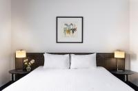 Un dormitorio con una cama blanca con dos lámparas. en Edit Auckland Central, en Auckland