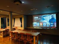 uma sala de jantar com mesa e cadeiras e um grande ecrã em Ember Lodge - Hakuba em Hakuba