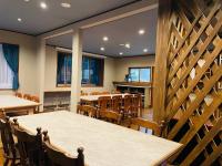 uma sala de jantar com mesas, cadeiras e janelas em Ember Lodge - Hakuba em Hakuba