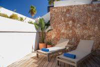 a patio with two chairs and a stone wall at Hotel & Spa Blau Parc in San Antonio