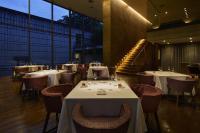 Un restaurante con mesas y sillas blancas y ventanas. en RISONARE Nasu, en Nasu