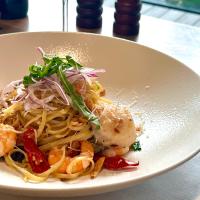 um prato branco de macarrão com camarão e vegetais em CP Hotel em Dayuan