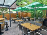 un patio con tavoli, sedie e ombrellone verde di Paradies 1 a Kastelhof