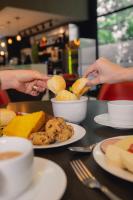 deux personnes se tendent la main pour attraper un morceau de nourriture sur une table dans l'établissement ibis BH Afonso Pena Savassi, à Belo Horizonte