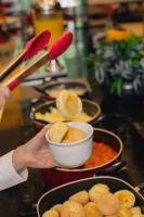 une personne tenant un bol de nourriture sur une table dans l'établissement ibis BH Afonso Pena Savassi, à Belo Horizonte