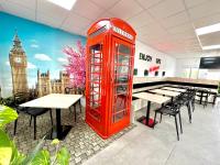 Una cabina telefónica roja en un restaurante con una torre de reloj. en Camping Totana Park, en Totana