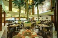 Un restaurante con mesas y sillas y palmeras. en Vivanta Goa, Panaji, en Panaji