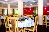 a restaurant with white tables and chairs and red walls at Hotel Orphey in Bansko