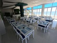 Un restaurante con mesas y sillas y el océano. en Recidencia Del Hamor Beach Front, en Santa Magdalena