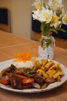 Un plato de comida con arroz y verduras y un jarrón de flores. en Hotel Santa Rosa, en Chiclayo